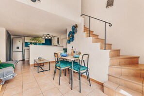 A modern kitchen with a dining area, a staircase, and a visible living room. - Apartment Le nid D'Azur by Sur la mer (Mandelieu-la-Napoule)