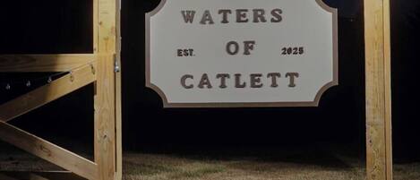 Une pancarte en bois portant l’inscription « WATERS OF CATLETT, fondé en 2025 », fixée sur une structure.