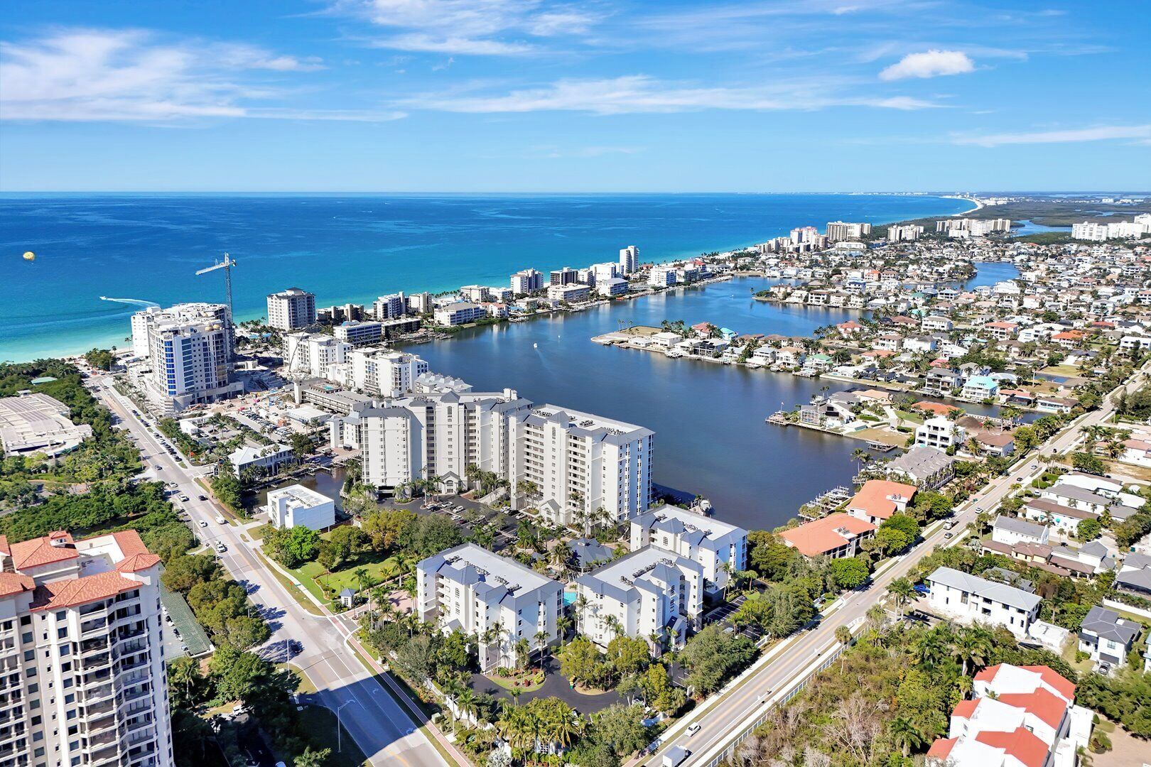 Un paisaje urbano costero con edificios altos, un puerto deportivo y un cielo azul despejado.