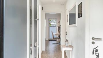 A hallway with a door leading to a dining area, a small table with a lantern, and a fire extinguisher on the wall.