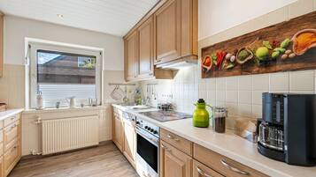Una cocina moderna con armarios de madera, estufa, pileta y ventana con persianas.