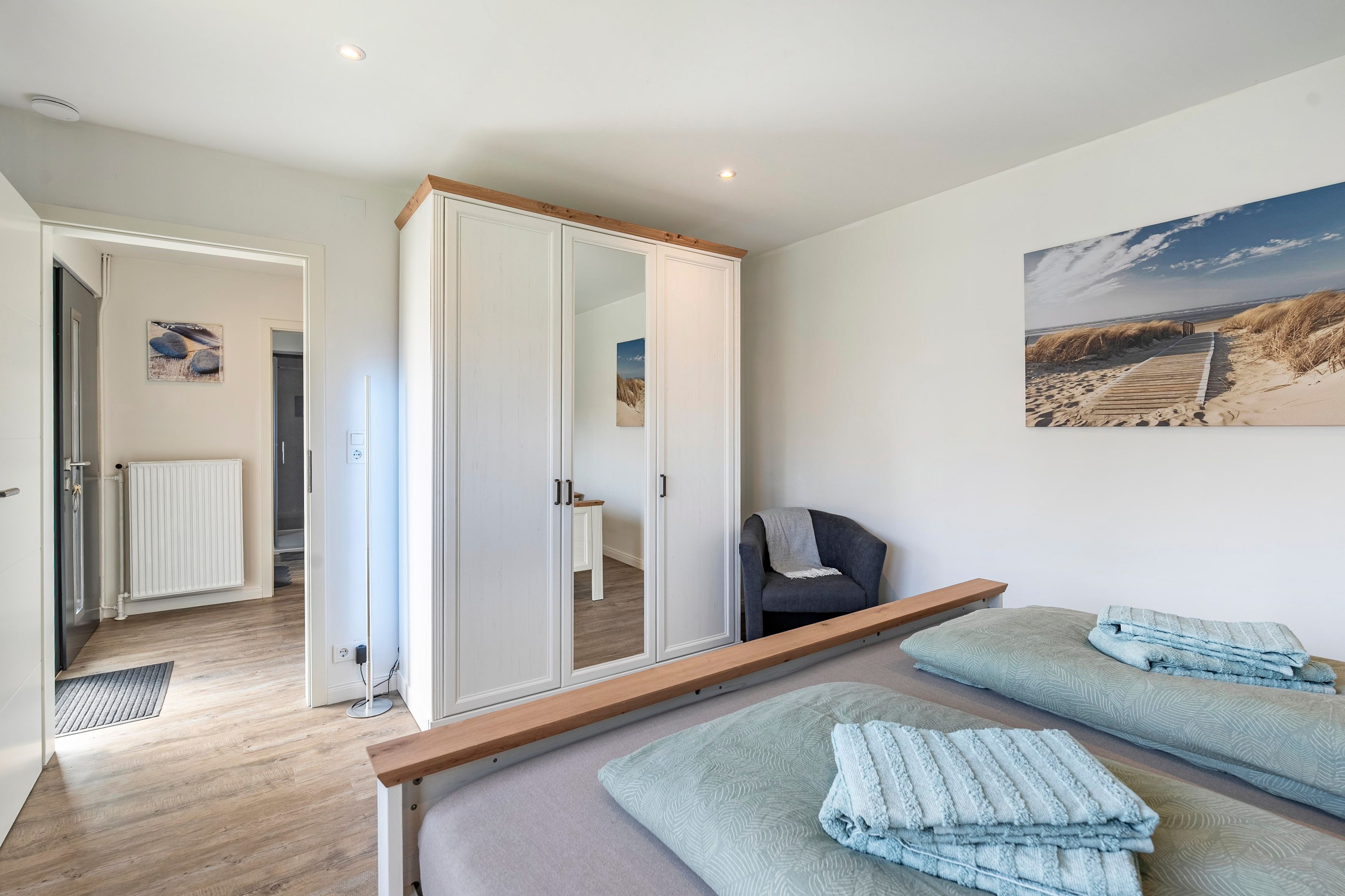 Ein Schlafzimmer mit einem Bett, einem Sessel, einem Kleiderschrank und einem Bild an der Wand.