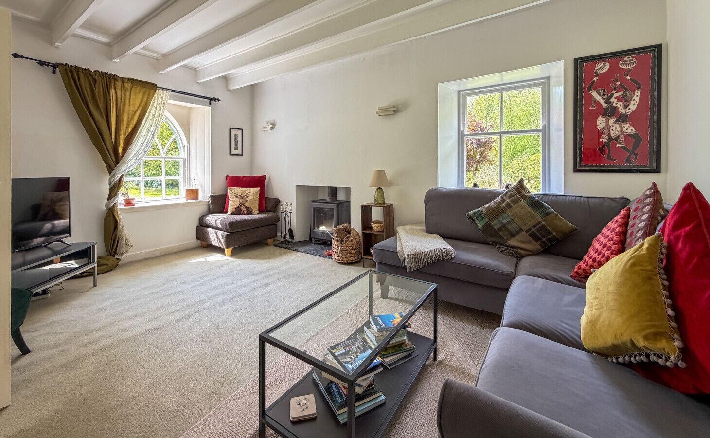 A living room with a sofa, a coffee table, a TV, a fireplace, and a window with curtains.