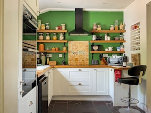 A kitchen with white cabinets, a green backsplash, and various kitchen appliances. - Charming Foresters Cottage in Blair Castle Estate (North Ayrshire Council)