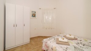 A bedroom with a bed, a wardrobe, a window with curtains, and a painting on the wall. - Apartment for 4 people in Dramalj with sea view & parking space (Dramalj)