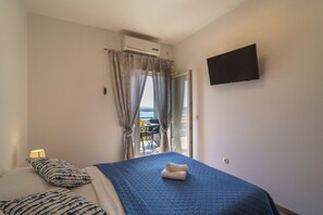 Ein Schlafzimmer mit Bett, Fernseher, Klimaanlage und Blick ins Freie.