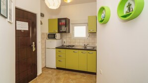 A kitchen with green cabinets, a microwave, a sink, and a hanging light fixture. - Apartment for 4 people in Dramalj with sea view & parking space (Dramalj)
