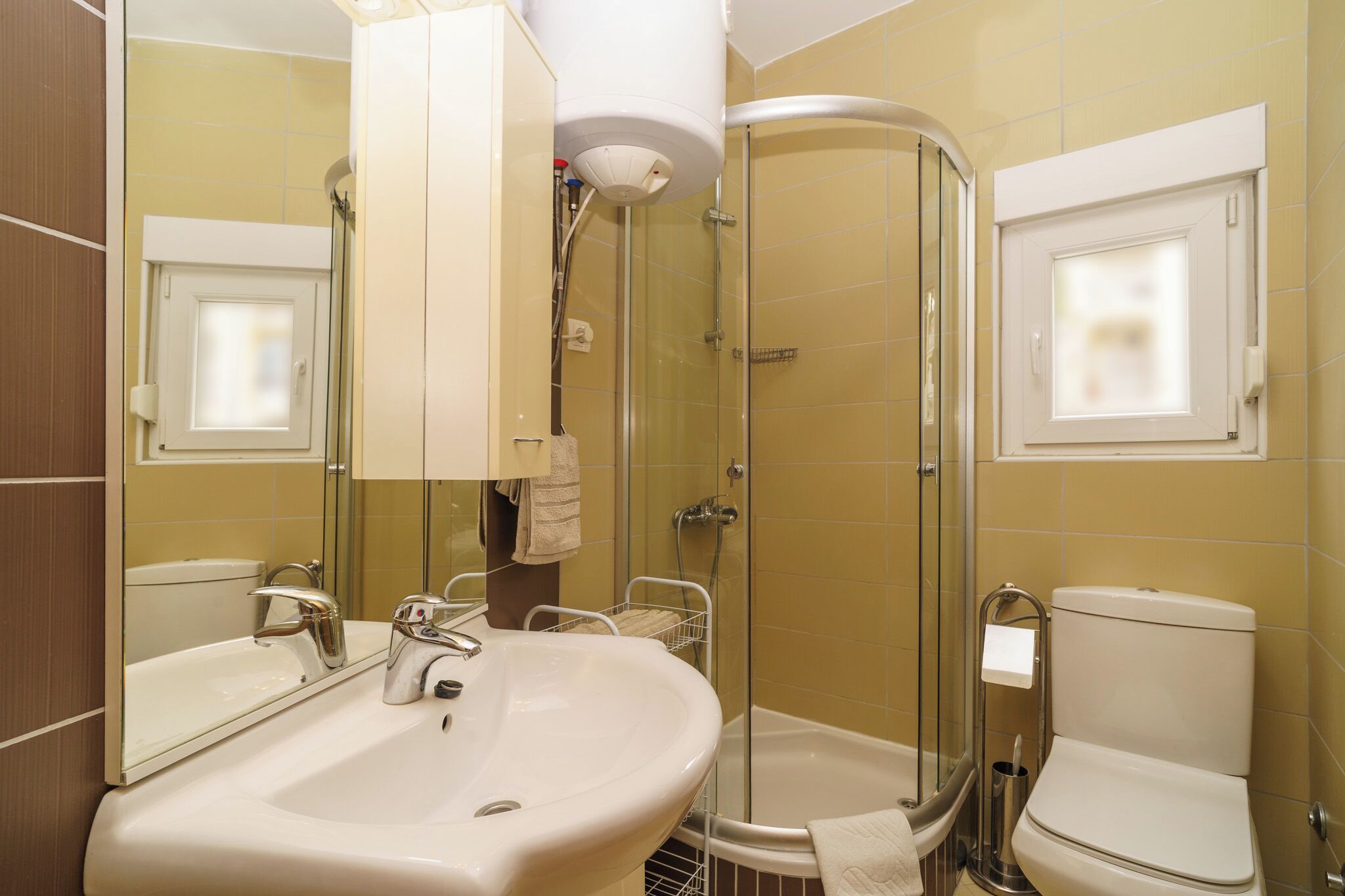 Een badkamer met een wastafel, spiegel, douche en toilet.