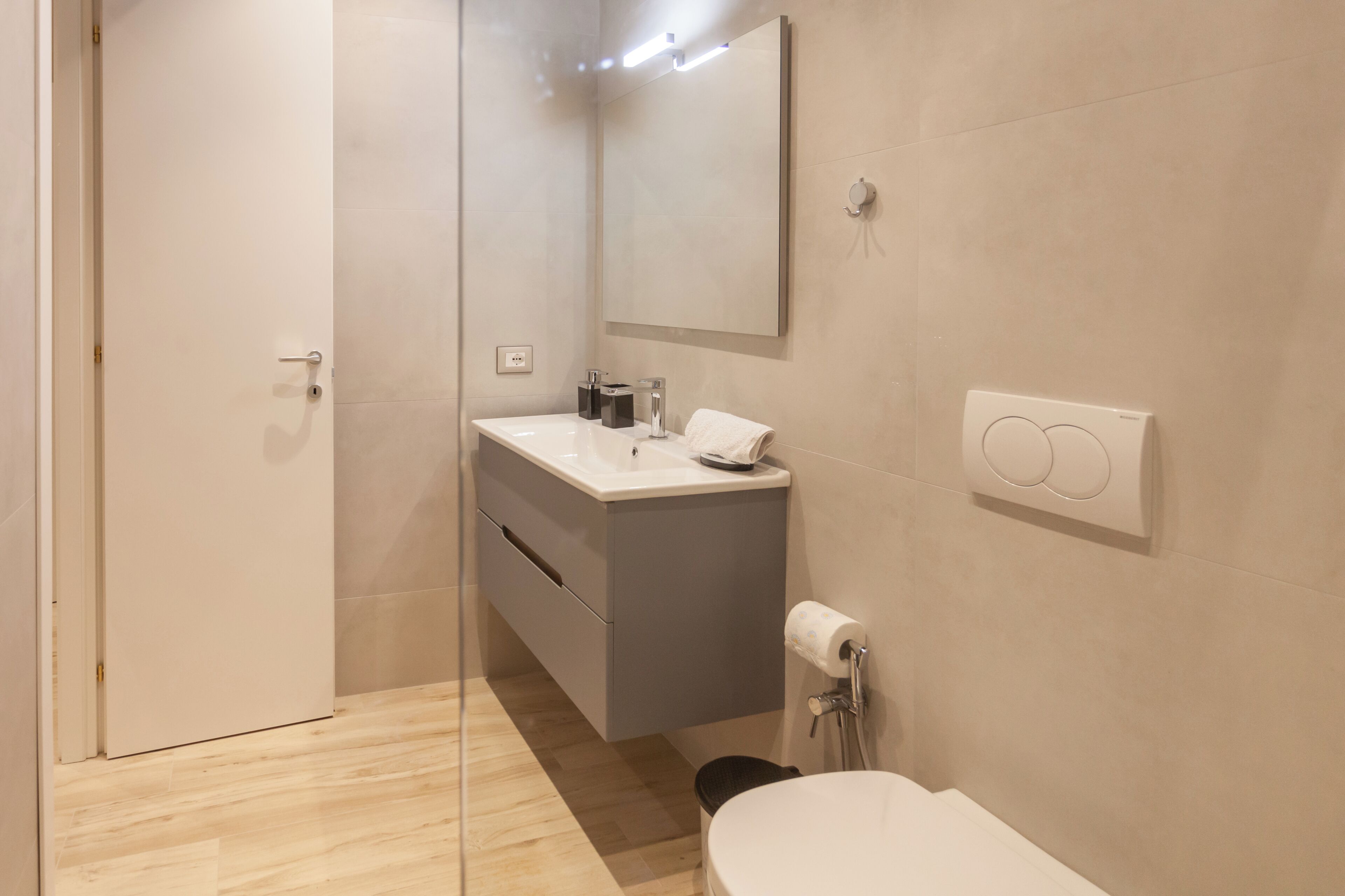 Ein modernes Badezimmer mit Toilette, Waschbecken, Spiegel und Dusche.
