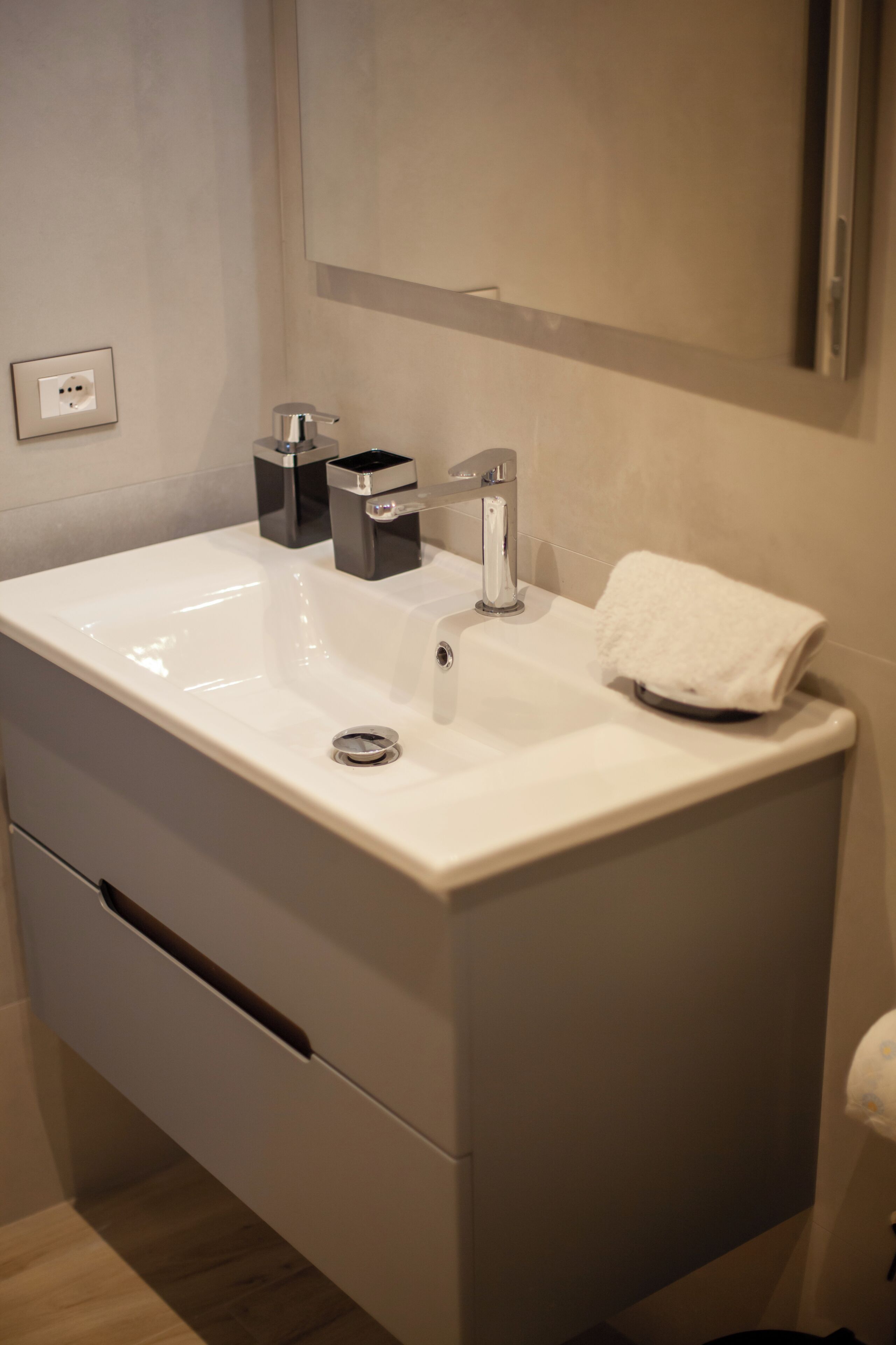 Ein modernes Badezimmer mit einem weißen Waschbecken, einem Chromarmaturen und einem Handtuch auf der Ablagefläche.