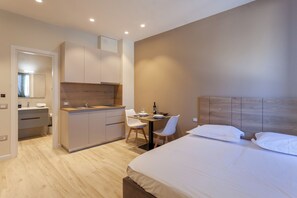 A modern hotel room with a bed, a small kitchenette, a dining area, and a bathroom. - Bus  The Station Apartments (Durrës)