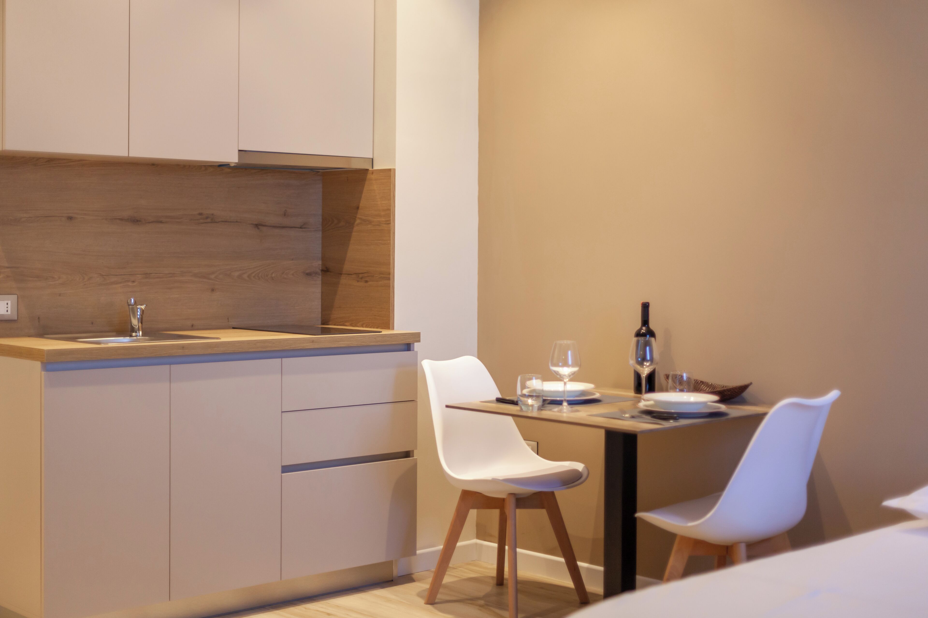 Una cucina moderna con un piano di lavoro in legno, mobili bianchi e due sedie bianche.