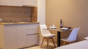 A modern kitchen with a wooden countertop, white cabinets, and two white chairs. - Bus  The Station Apartments (Durrës)