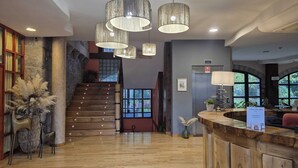 A hotel lobby with a wooden staircase, a reception desk, and multiple hanging pendant lights. - Antiguas Eras Hotel (La Alberca)