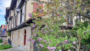 A traditional building with a stone facade, a visible entrance, and a tree with purple flowers. - Antiguas Eras Hotel (La Alberca)