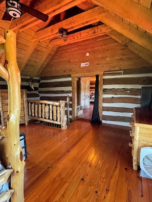 L’intérieur d’une cabane en rondins, avec un plancher en bois, un plafond en bois et un décor rustique.
