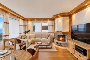 Un salon chaleureux avec une cheminée, un grand téléviseur à écran plat et un canapé confortable.