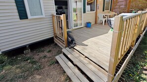 Ein Wohnmobil mit einer Terrasse, einer überdachten Veranda und einem sichtbaren Küchenbereich.