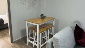 Et lille rum med et træbord og bænk, en grå sofa og en dekorativ vægdekoration.