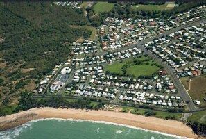 An aerial view of a coastal residential area with organized housing, roads, and a beach.