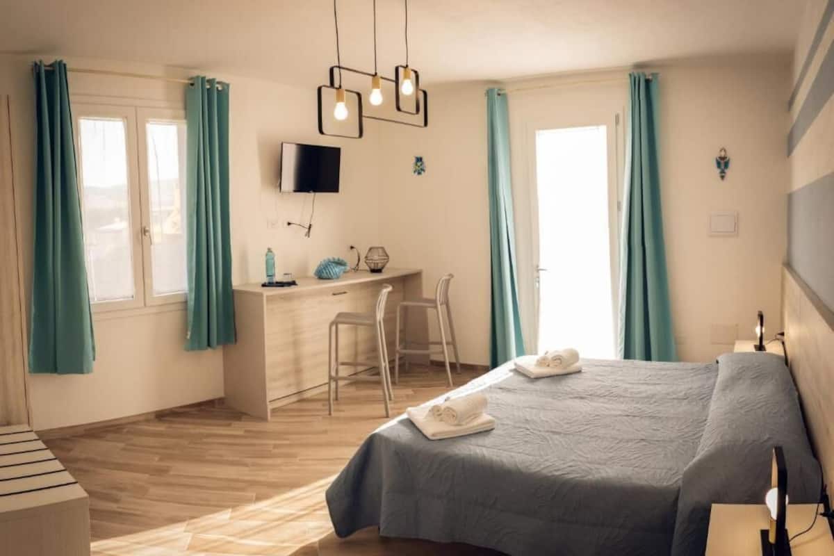 A hotel room with a bed, desk, chair, and a TV mounted on the wall.