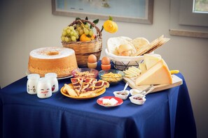 Une table garnie d’une variété d’aliments, notamment un gâteau, du fromage, du pain et des condiments.