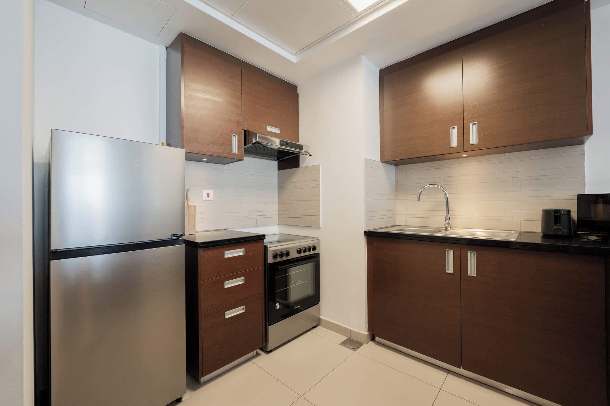 A modern kitchen with stainless steel appliances, wooden cabinets, and a tiled backsplash.