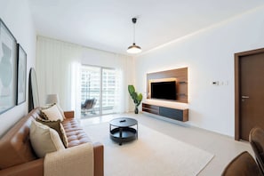 Ein modernes Wohnzimmer mit einer Ledersofa, einem runden Couchtisch, einem flachbildfernseher, der an einem Holzpaneel befestigt ist, und einem großen Fenster mit Blick auf Gebäude.