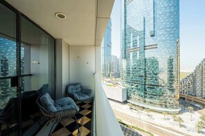 Ein Balkon mit zwei Stühlen, einem Schachbrettfußboden und Blick auf moderne Hochhäuser.
