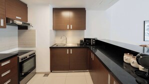 A modern kitchen with dark wooden cabinets, a stainless steel sink, and a black countertop. - Modern 1BR Living at Reem Island by Vanilla Homes (Abu Dhabi)