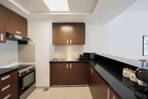 Eine moderne Küche mit dunklen Holzschränken, einer Edelstahl-Spüle und einer schwarzen Arbeitsplatte.