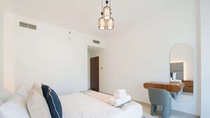 A modern hotel room with a bed, a desk, a chair, and a mirror. - Modern 1BR Living at Reem Island by Vanilla Homes (Abu Dhabi)
