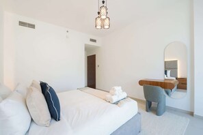 Ein modernes Hotelzimmer mit Bett, Schreibtisch, Stuhl und Spiegel.