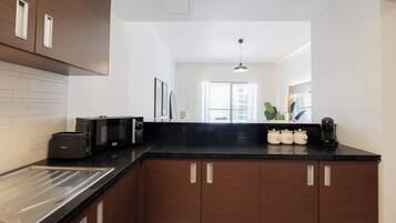 A modern kitchen with dark wooden cabinets, a black countertop, and a built-in oven.