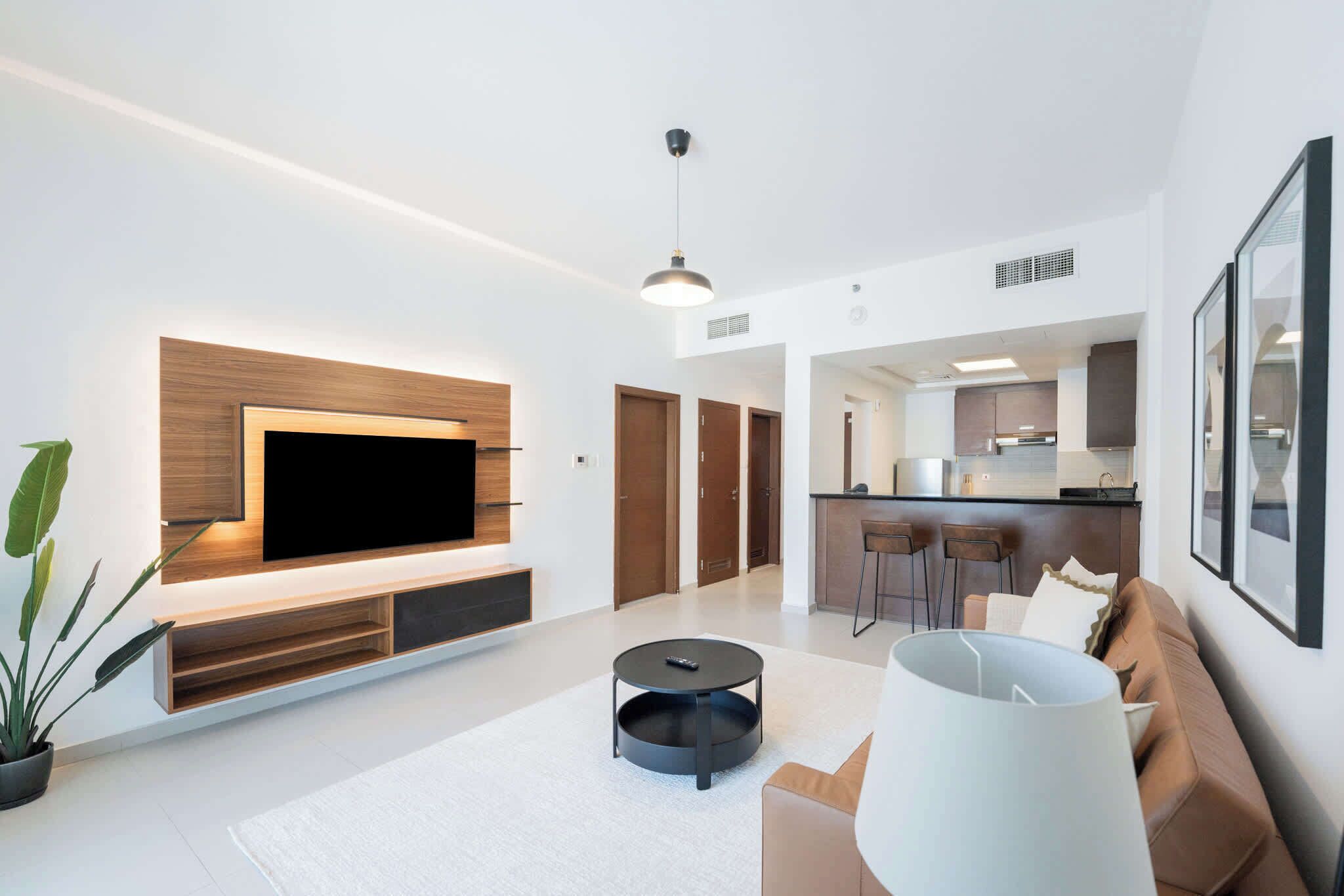 A modern living room with a flat-screen TV, a round coffee table, and a sofa.