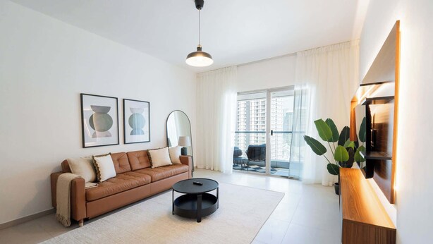 A modern living room with a brown leather sofa, a round black coffee table, and a large window with curtains. - Modern 1BR Living at Reem Island by Vanilla Homes (Abu Dhabi)