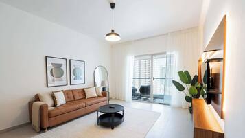 A modern living room with a brown leather sofa, a round black coffee table, and a large window with curtains.