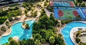 Ein Pool, umgeben von Palmen, und ein Basketballplatz.