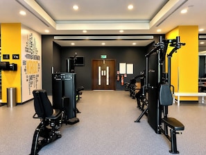 A gym with exercise equipment, a wall with motivational words, and a door with emergency exit signs. - Vanilla Homes Premium 1BR in Reem Island (Abu Dhabi)