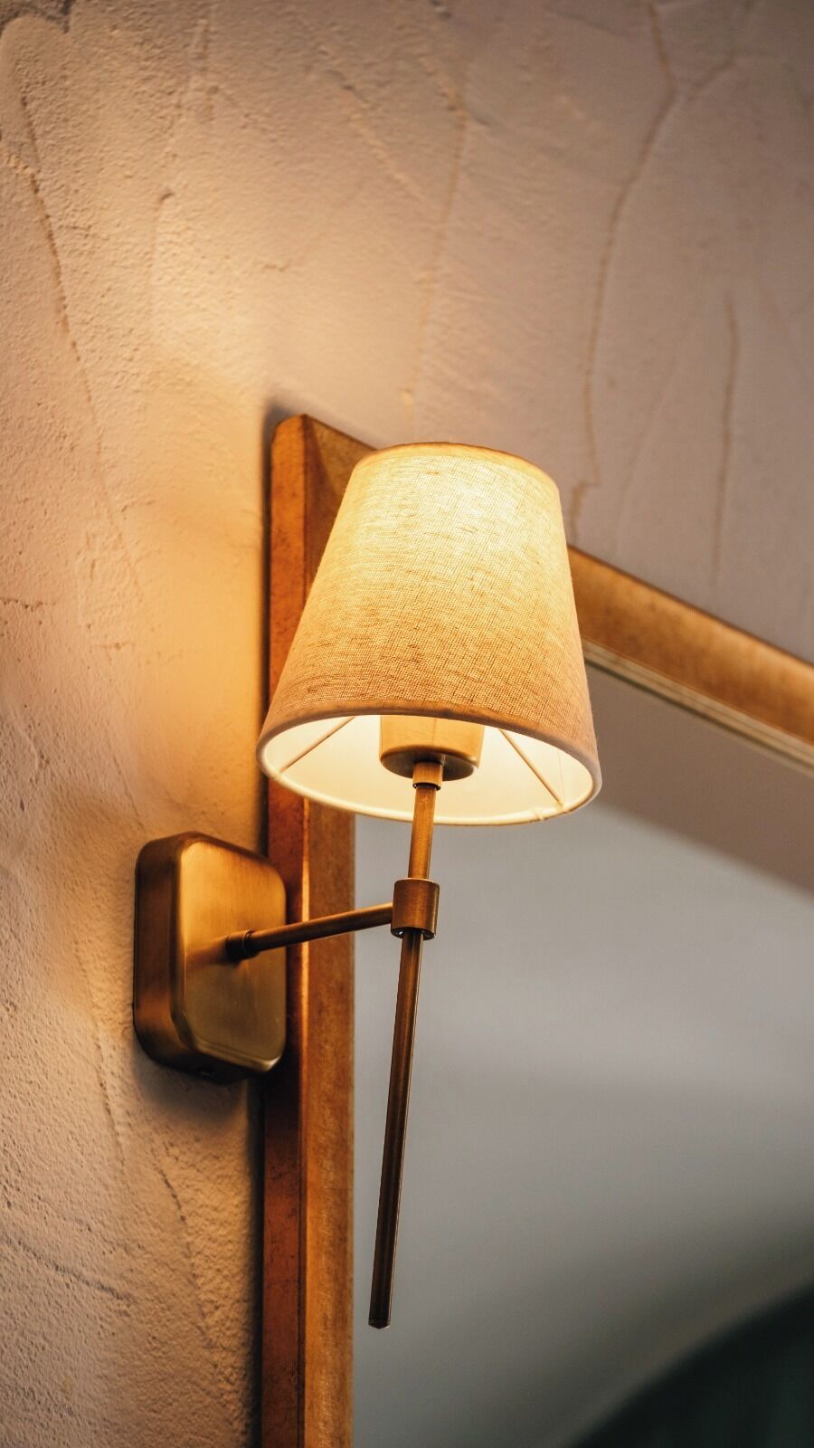 Une lampe murale dotée d’un abat-jour en tissu et d’un pied en métal.