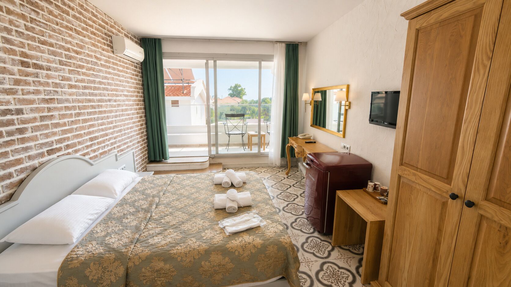 A hotel room with a bed, a desk, a wardrobe, a television, and a view of the outside.