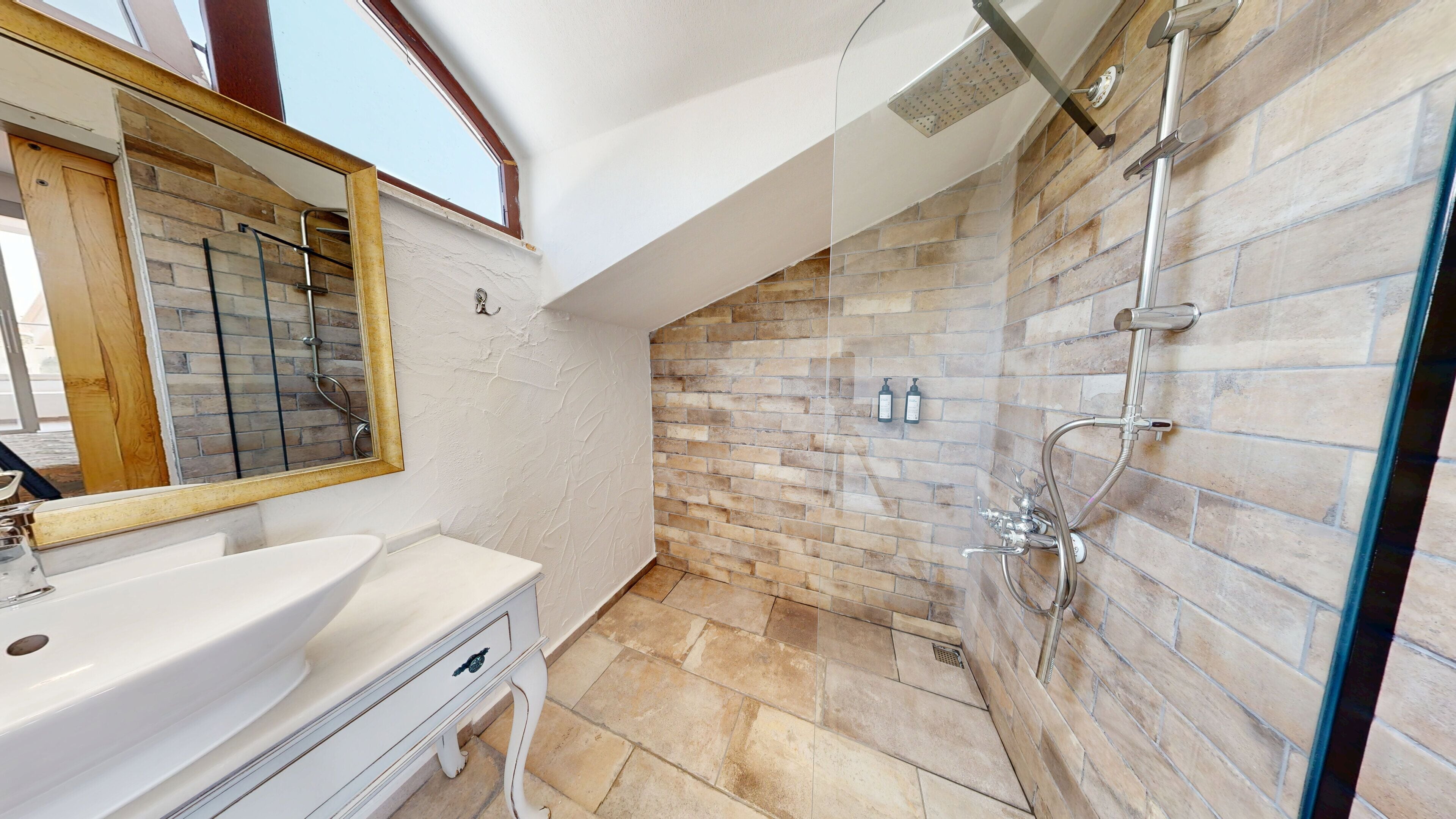 A bathroom with a white vanity, a glass shower enclosure, and a stone-tiled shower wall.
