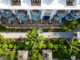 A multi-level hotel with outdoor seating areas, a covered walkway, and lush greenery.