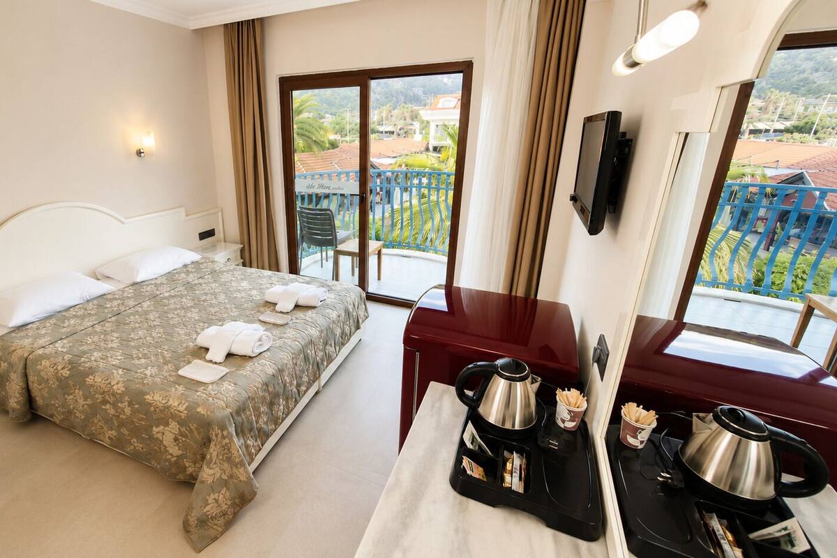 A hotel room with a bed, bedside table, and a view of the outside.
