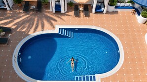 An aerial view of a swimming pool with a person in the water, surrounded by lounge chairs and umbrellas. - del Mare Hotel Ölüdeniz (Fethiye)