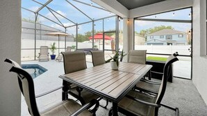 Überdachte Terrasse mit Pool, Sitzgelegenheit im Freien und Blick auf Häuser.