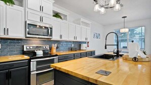 Eine moderne Küche mit weißen Schränken, einer Holz Arbeitsplatte, einem eingebauten Backofen und einer Edelstahl-Dunstabzugshaube.
