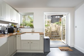 Eine moderne Küche mit großem Fenster, integriertem Spülbecken und einem kompakten Geschirrspüler.
