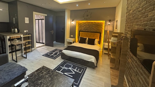 A modern bedroom with a bed, bedside tables, a desk, and a seating area. - Nova Park Suites (İstanbul)