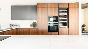 Eine moderne Küche mit Holzausstattung, einem Einbauofen und einer Kaffeemaschine.